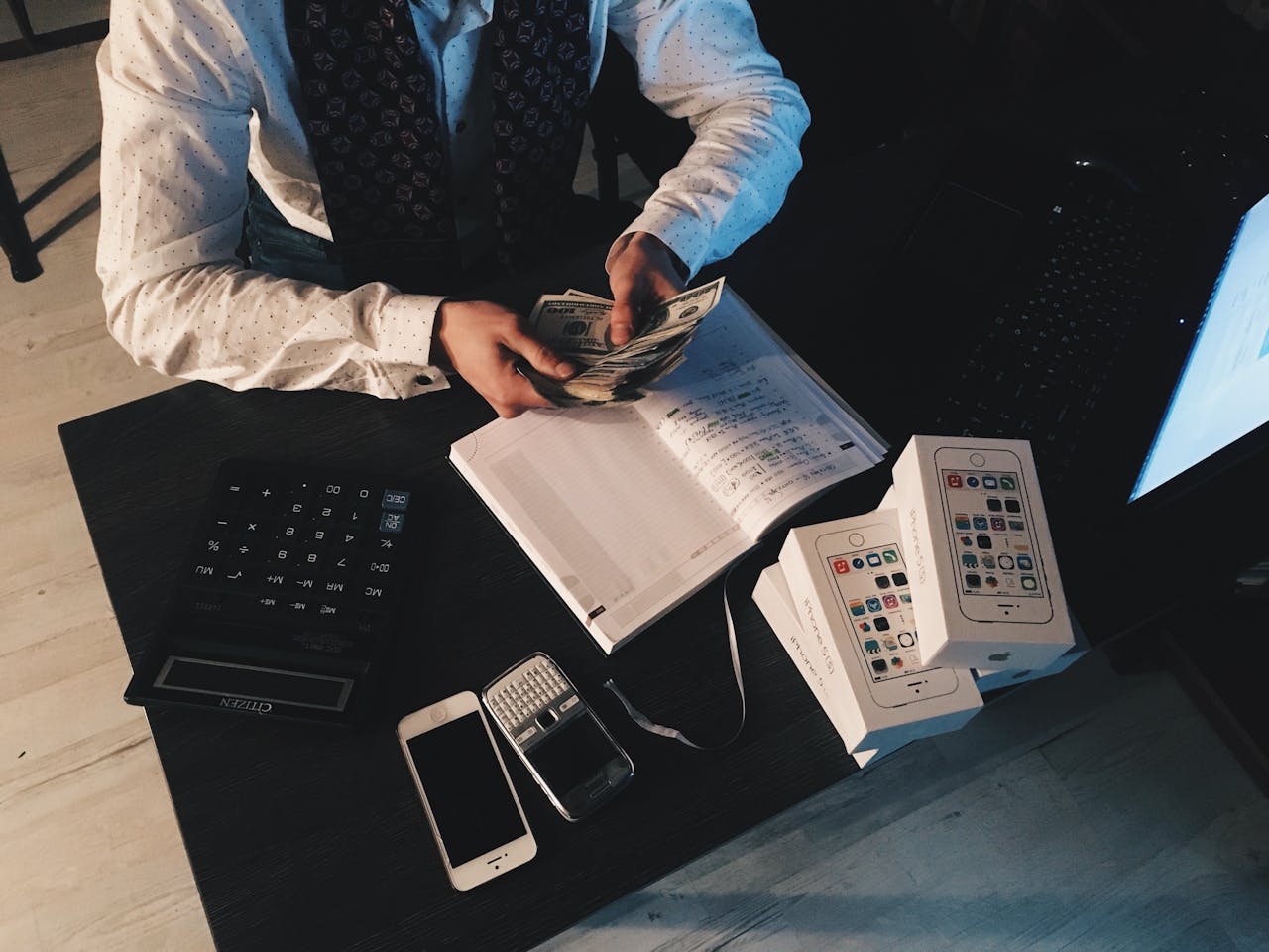 Avaleht Businessman organizing finances with tech devices and cash on desk.