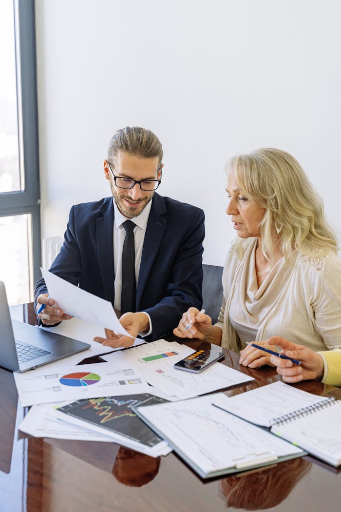 Meist Two business professionals reviewing financial documents and graphs during a meeting.